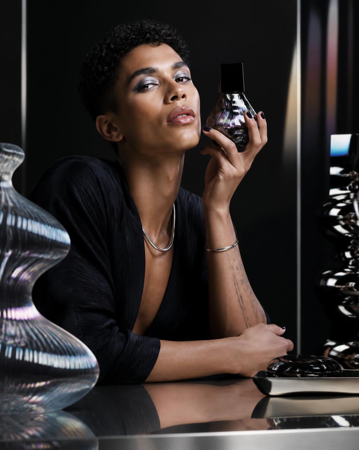 Editorial beauty model presenting a sculptural fragrance bottle